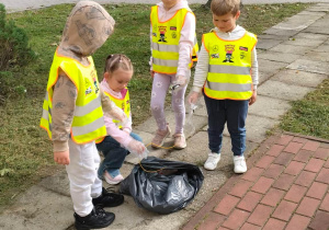 Dzieci sprzątają teren w pobliżu przedszkola
