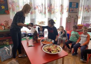 Dziecko wkłada marchewkę i jabłko do sokowirówki.