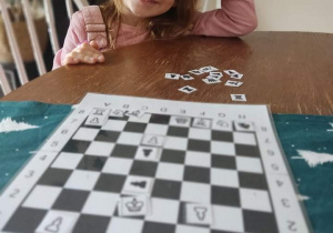 Dziewczynka gra w szachy z rodzicami w domu