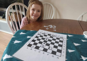 Dziewczynka gra w szachy z rodzicami w domu