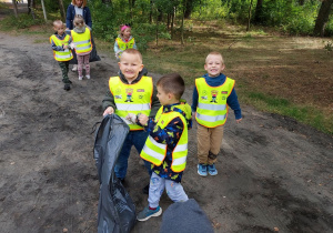 Dzieci sprzątają teren wokół przedszkola.