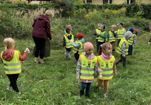 Dzieci sprzątają teren wokół przedszkola.