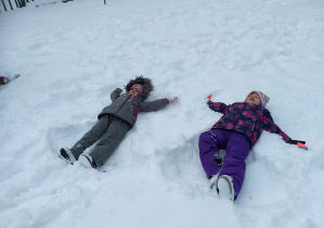 dziewczynki robią aniołki na śniegu