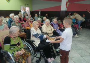 Chłopiec częstuje mieszkańców słodkościami