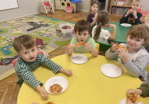 Dzieci jedzą pizzę