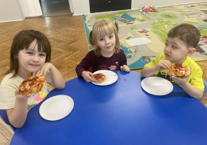 Dzieci jedzą pizzę