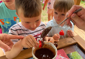 Dzieci jedzą truskawki i banany
