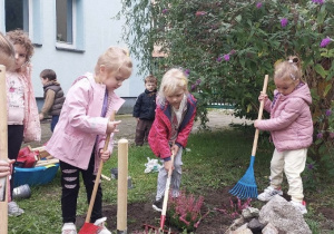 Dzieci robią porządki w ogrodzie i sadzą kwiaty