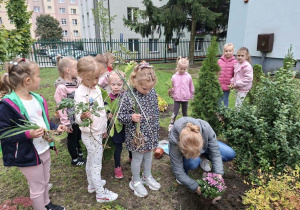 Dzieci robią porządki w ogrodzie i sadzą kwiaty